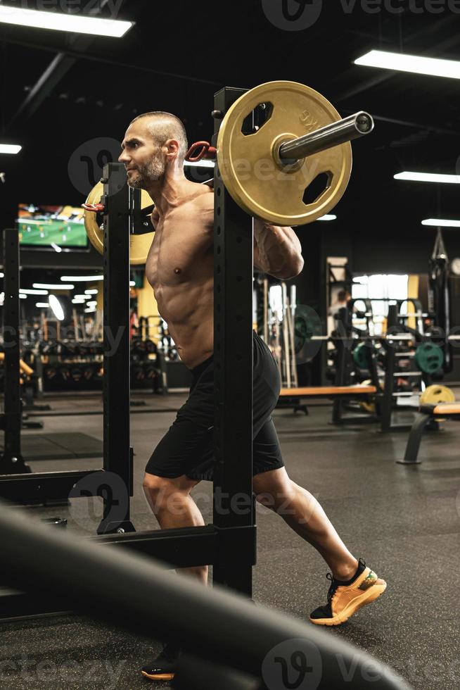 Bodybuilder during his workout with a barbell in the gym photo