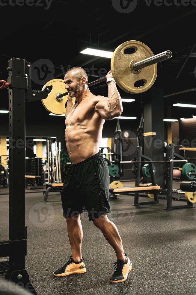 Bodybuilder during his workout with a barbell in the gym photo