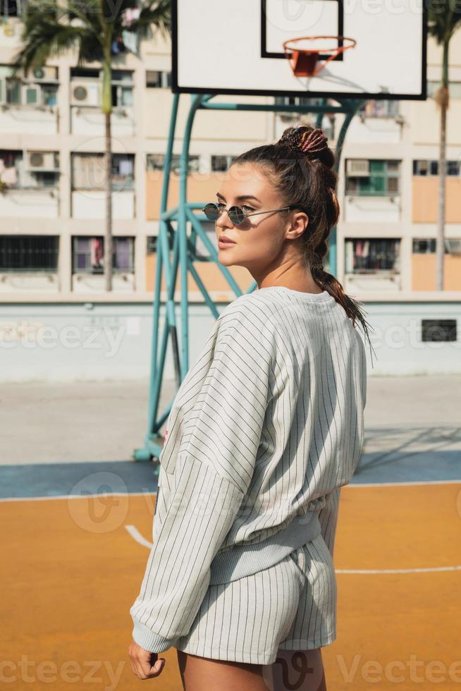 joven mujer con estilo está posando en la cancha de baloncesto choi hung estate foto