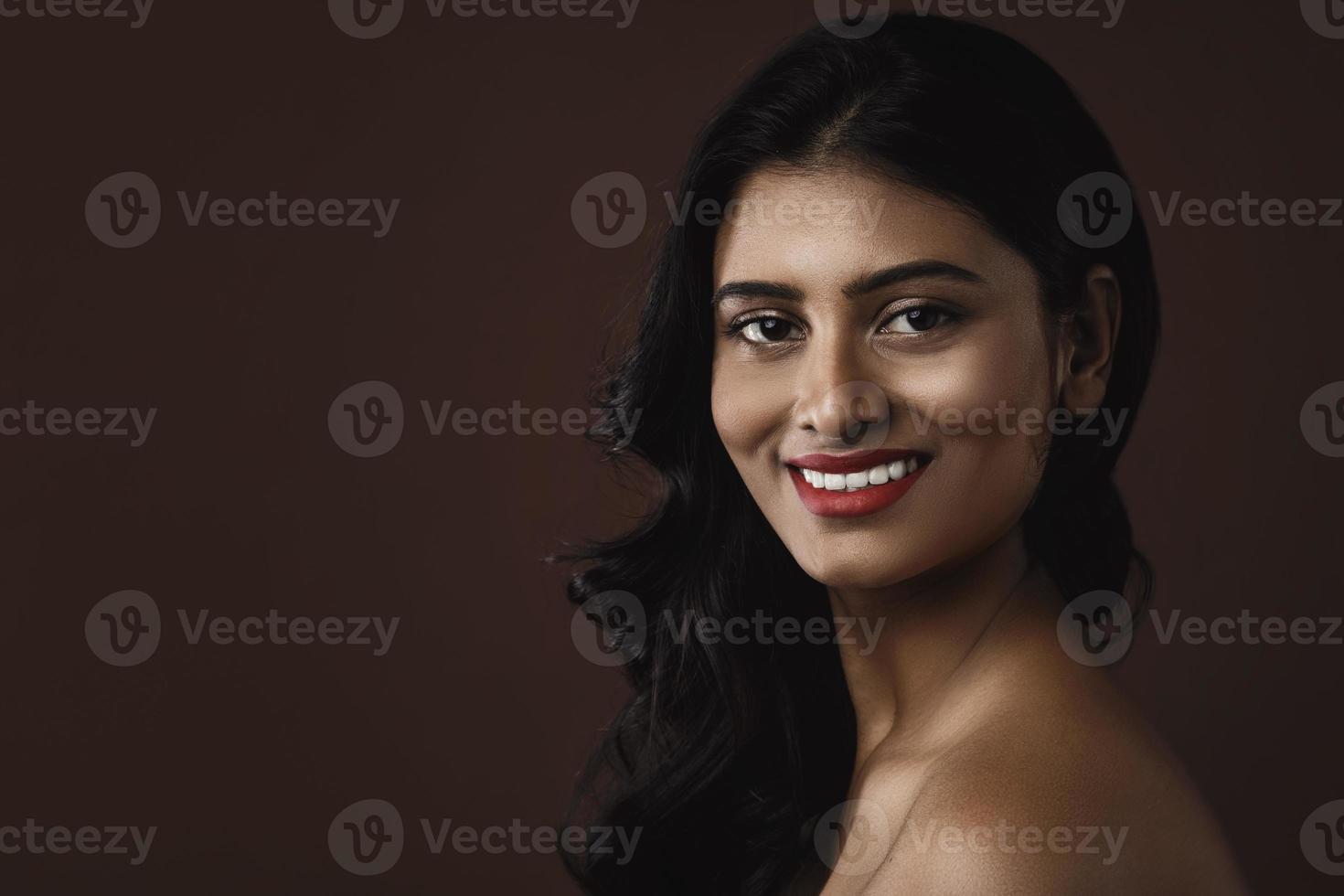 Indian woman with beautiful makeup and hairstyle on brown background photo