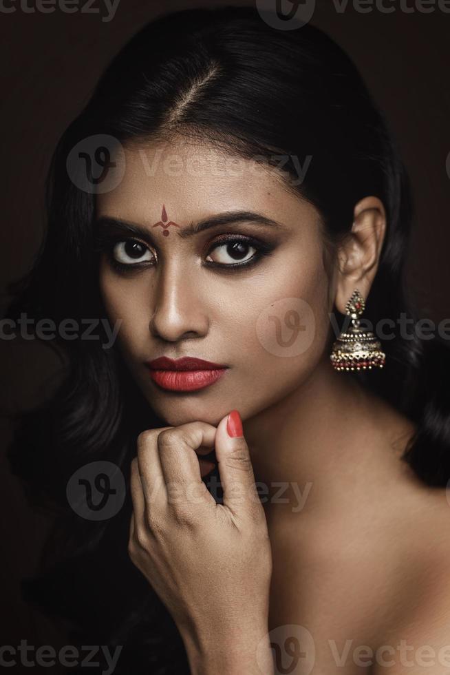 Portrait of Indian woman with beautiful makeup and hairstyle on brown background photo