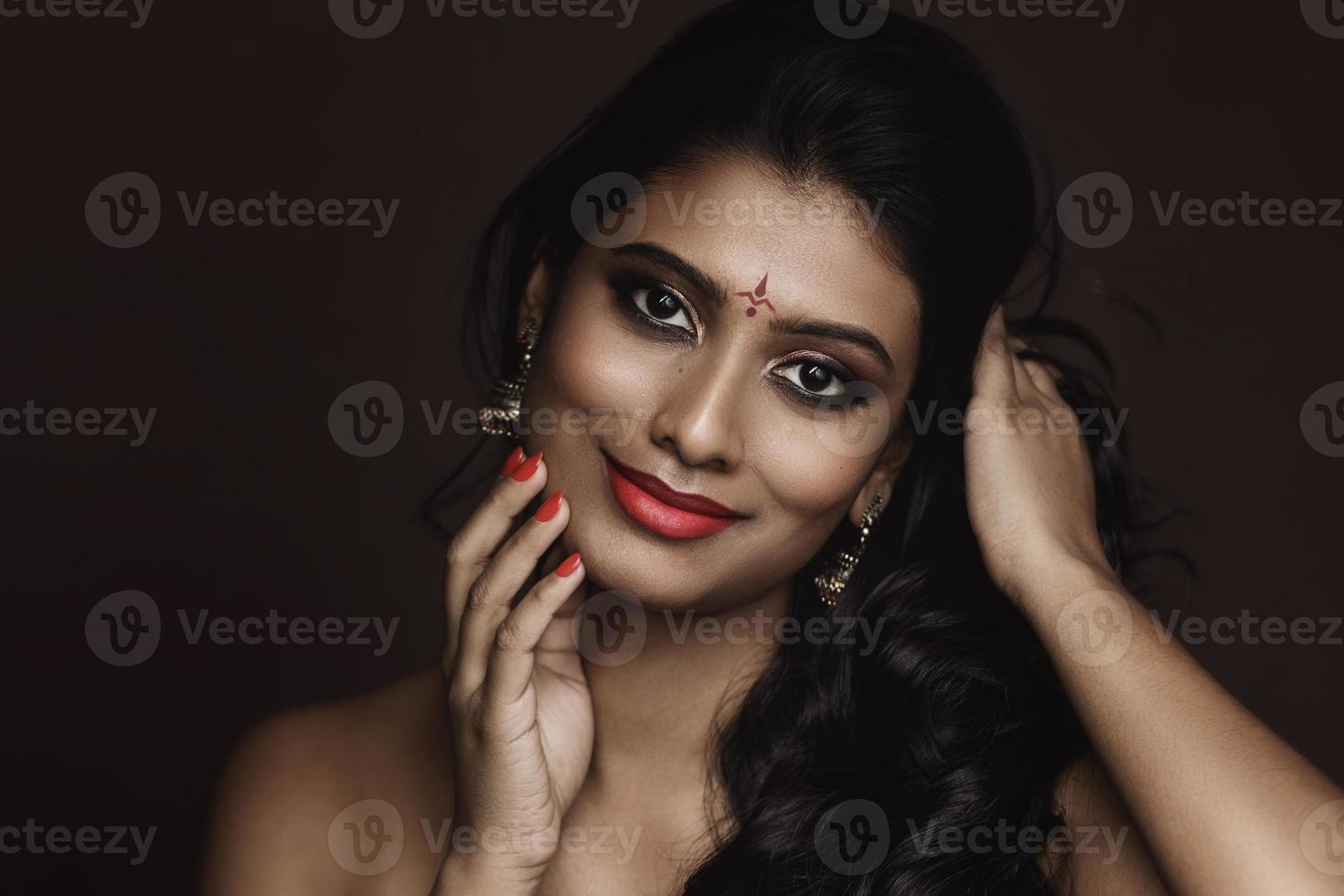 Portrait of Indian woman with beautiful makeup and hairstyle on brown background photo