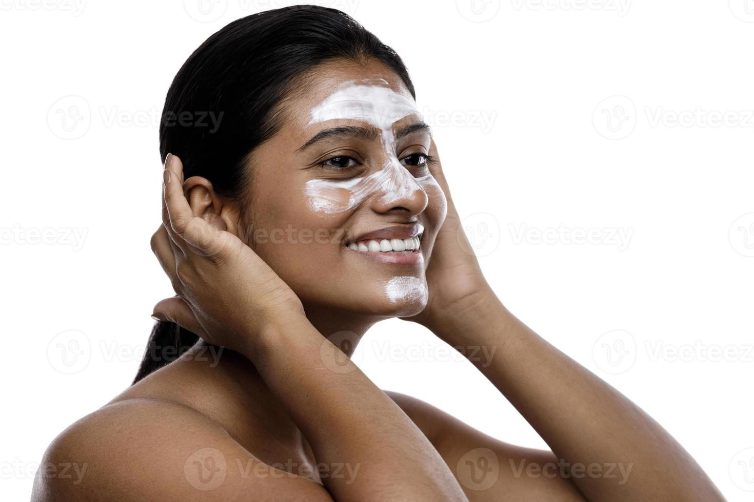 Young indian woman with a cleansing mask applied on her face photo