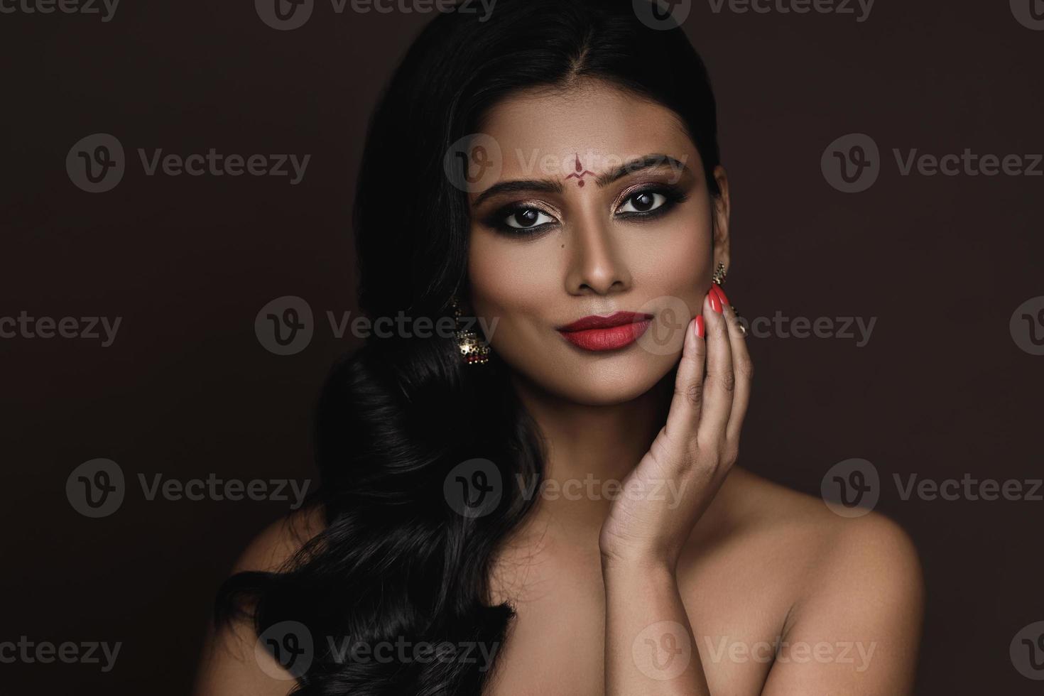 Portrait of Indian woman with beautiful makeup and hairstyle on brown background photo