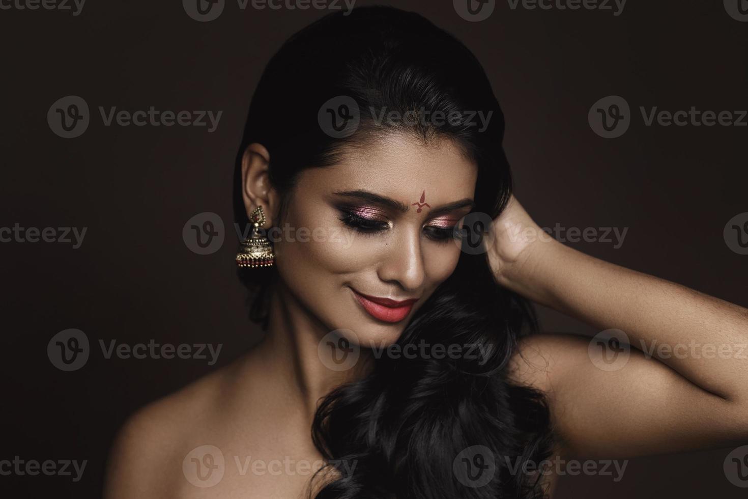 Portrait of Indian woman with beautiful makeup and hairstyle on brown background photo