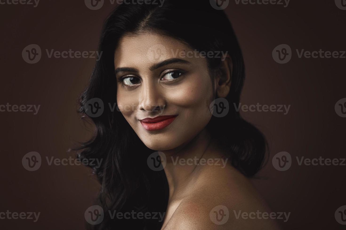 Indian woman with beautiful makeup and hairstyle on brown background photo