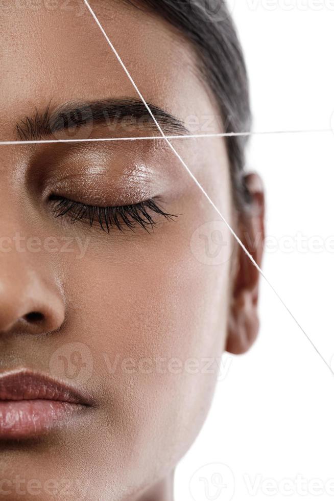 Eyebrow threading - epilation procedure for brow shape correction photo