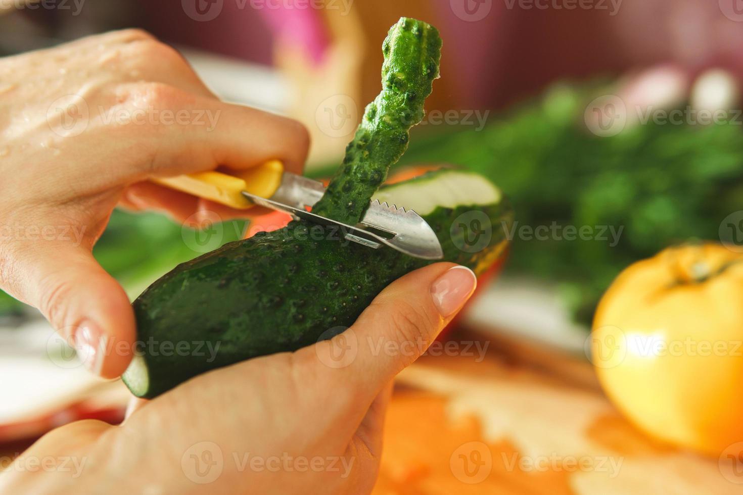 Female hand with peeler and cucumber photo
