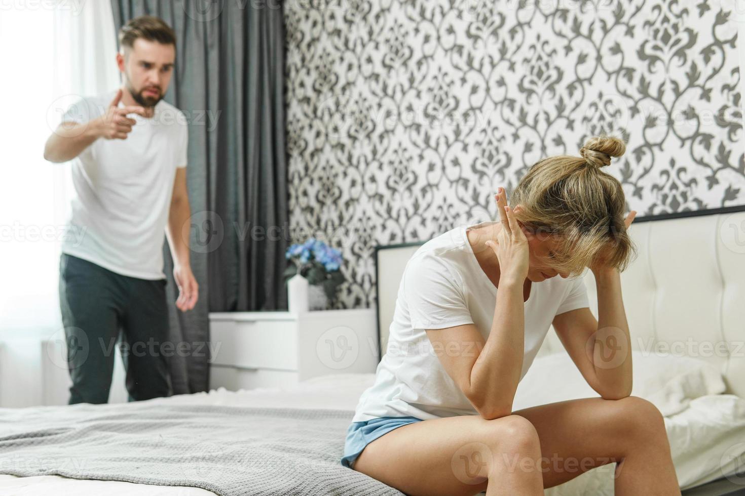 hombre enojado y mujer triste. pareja en conflicto en el dormitorio en casa. conceptos de engaño y desconfianza o violencia doméstica. foto