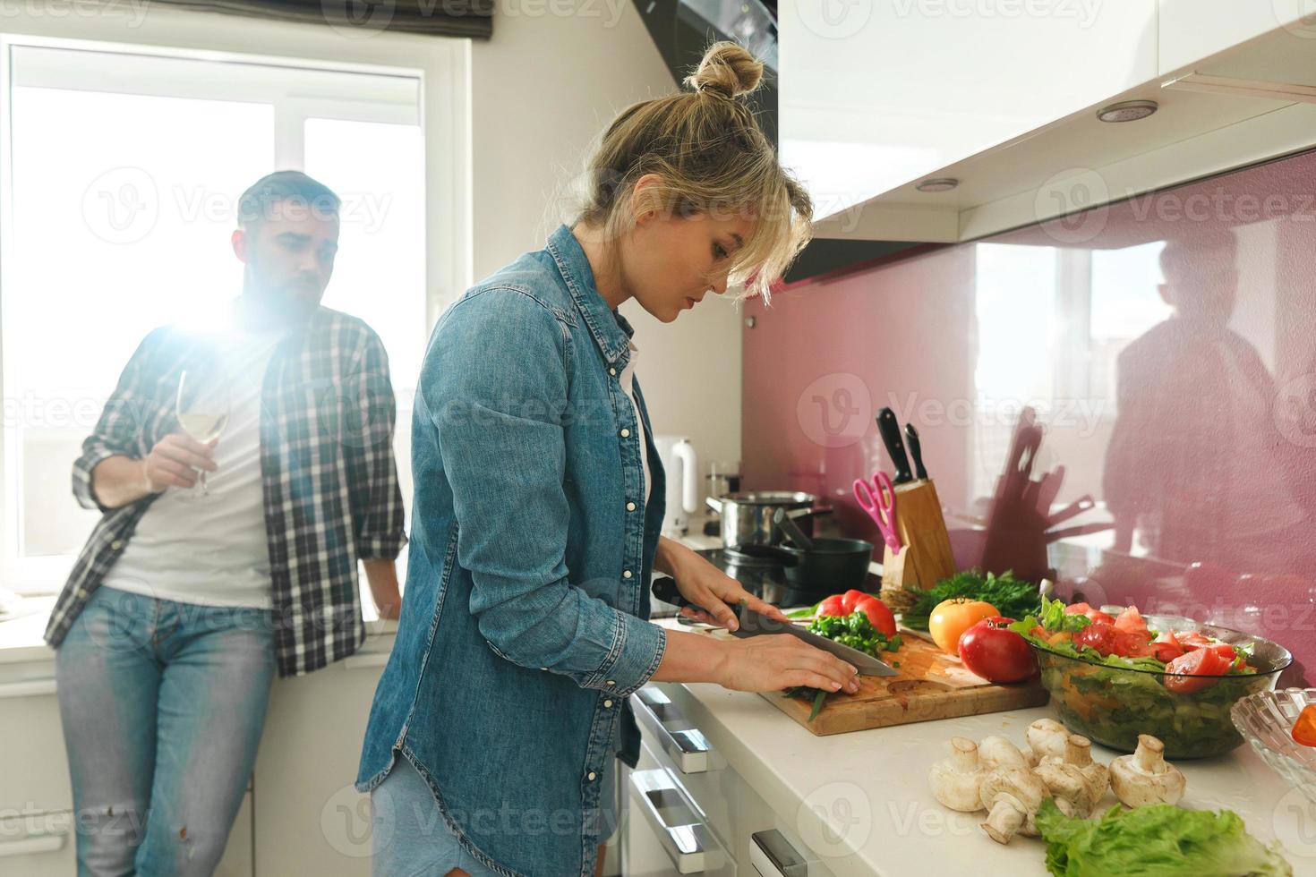 pareja feliz cocinando lanzamiento y bebiendo vino juntos en la cocina foto