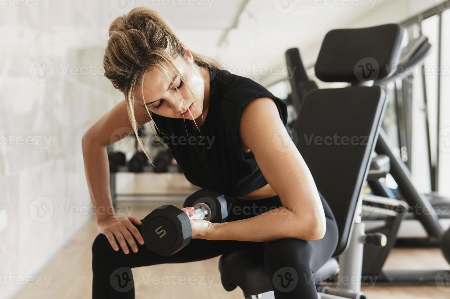 Athletic woman doing bicep curl exercise with a dumbbells in the gym photo
