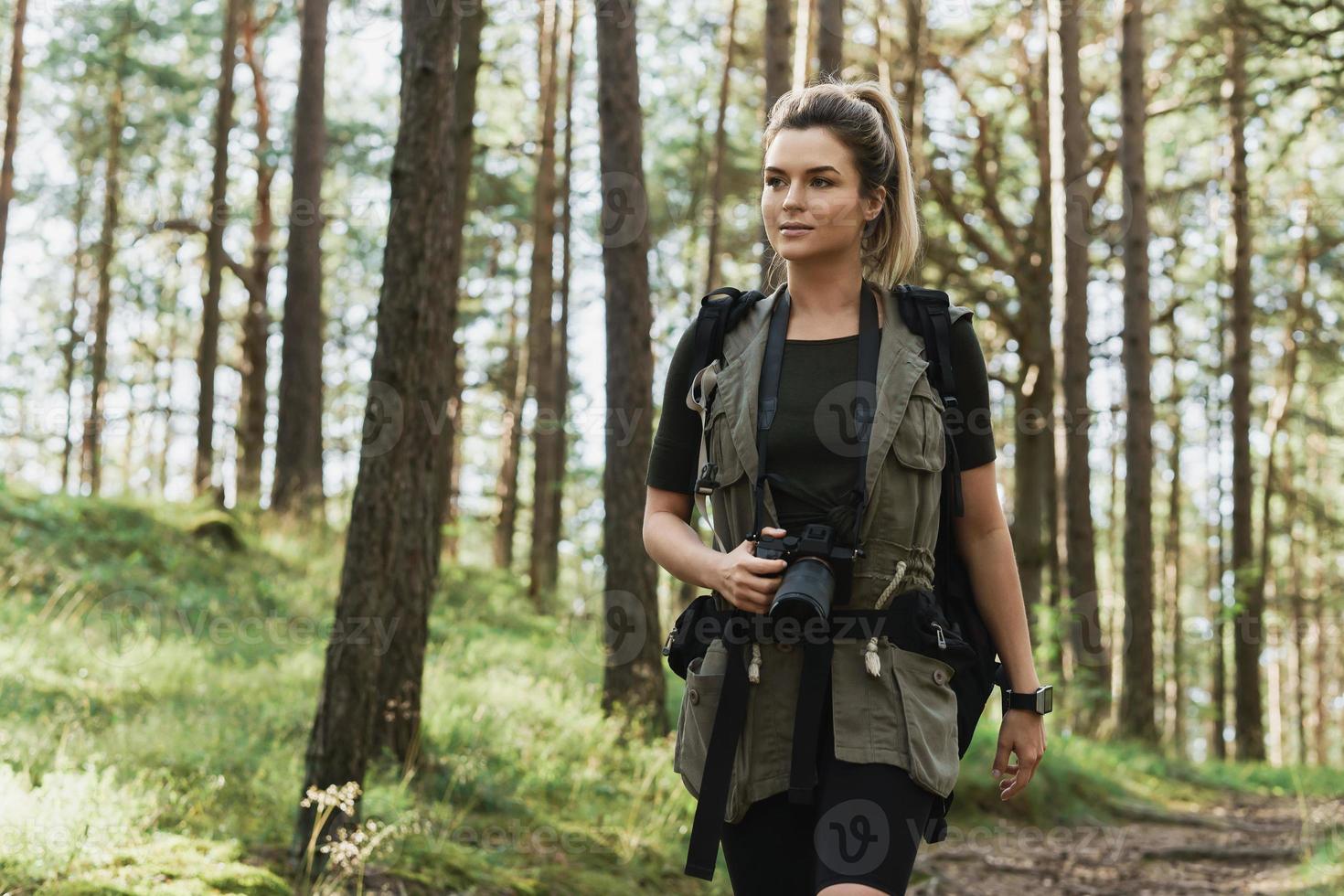 Woman hiker walking with a backpack and modern mirrorless camera photo