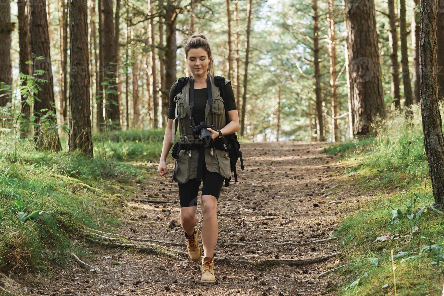 Woman hiker walking with a backpack and modern mirrorless camera photo