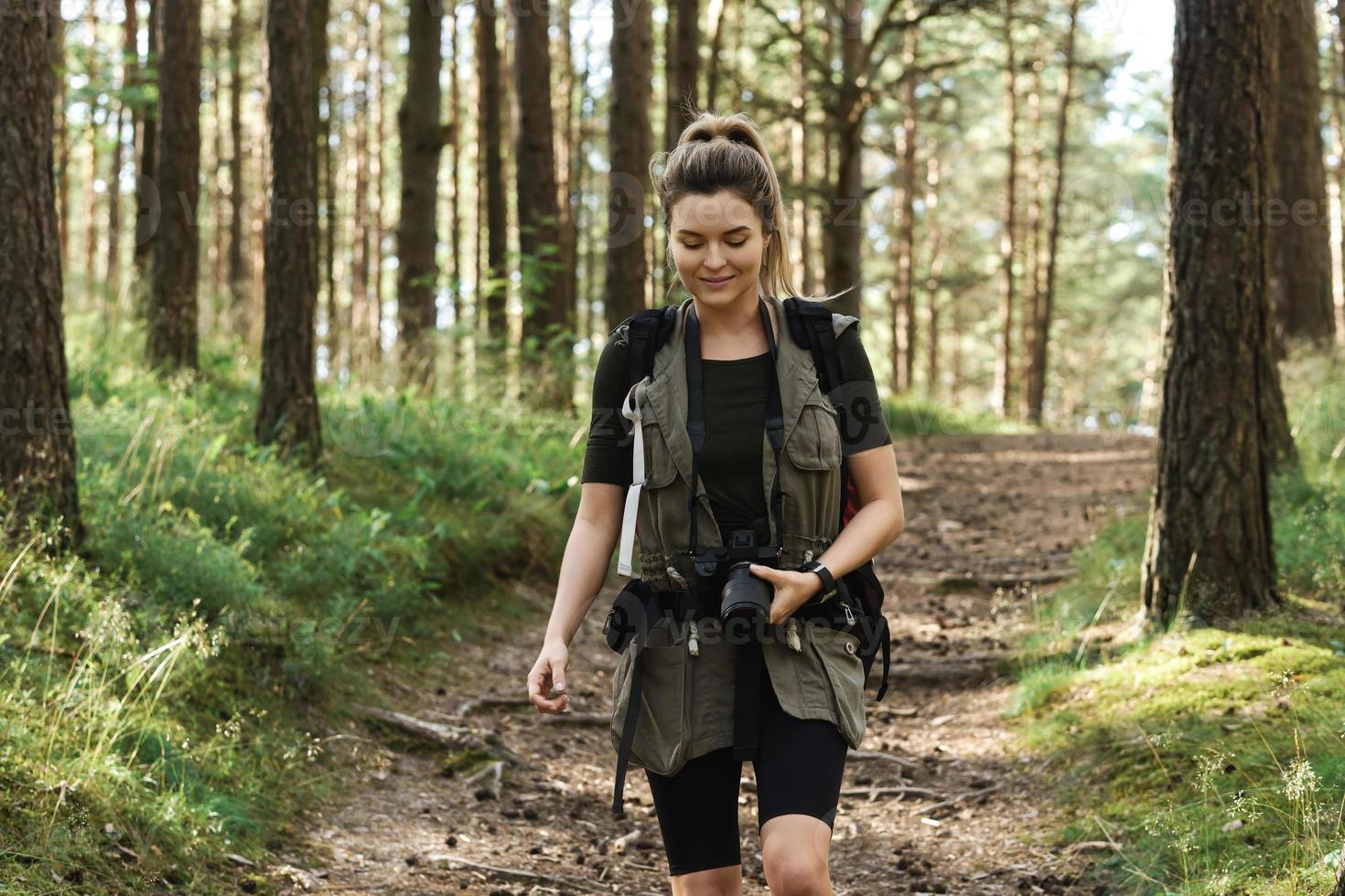 Woman hiker walking with a backpack and modern mirrorless camera photo