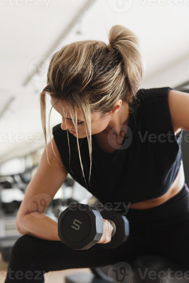 Athletic woman doing bicep curl exercise with a dumbbells in the gym photo