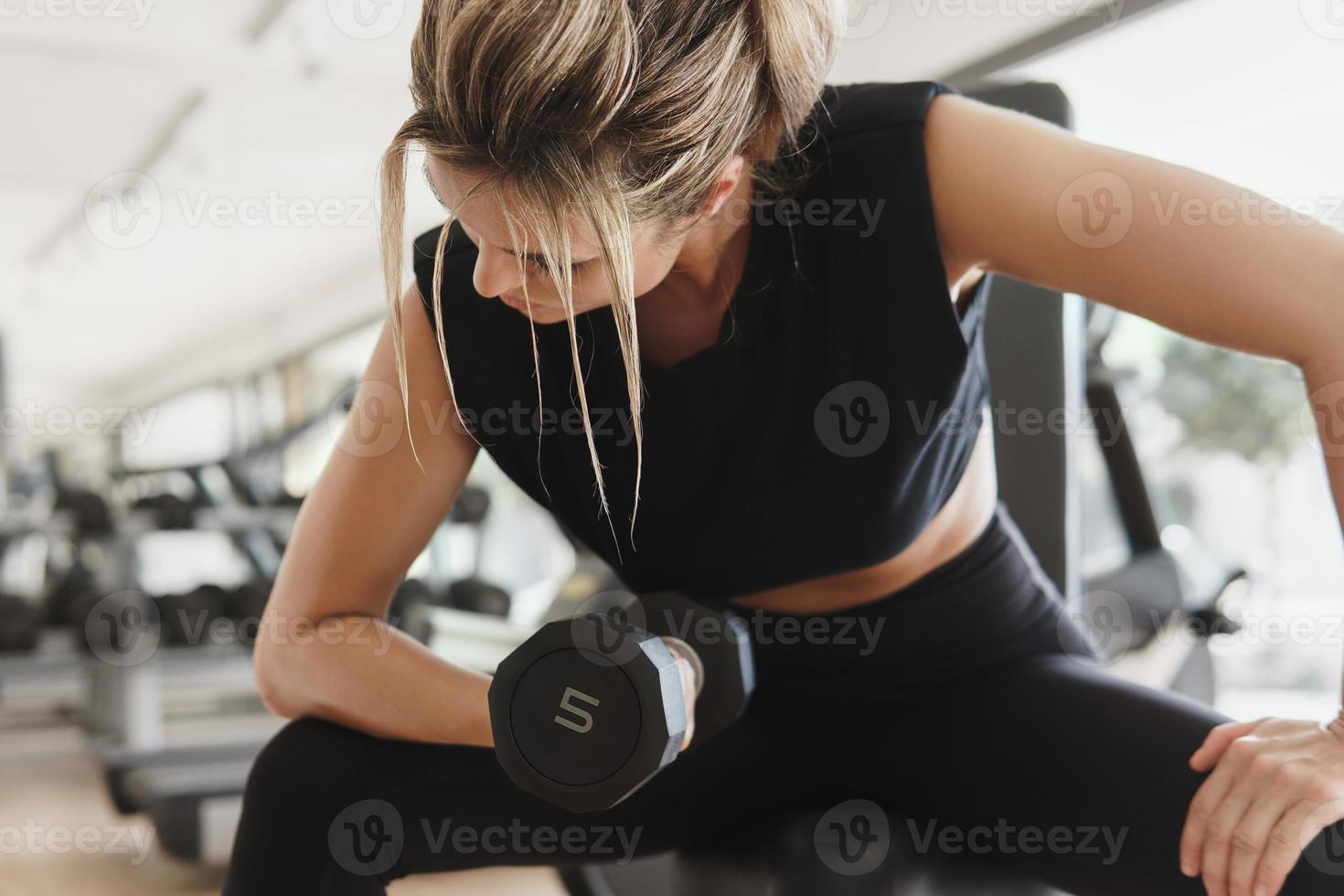 Athletic woman doing bicep curl exercise with a dumbbells in the gym photo