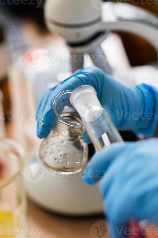 Scientist pouring substance from one flask to another in a laboratory photo