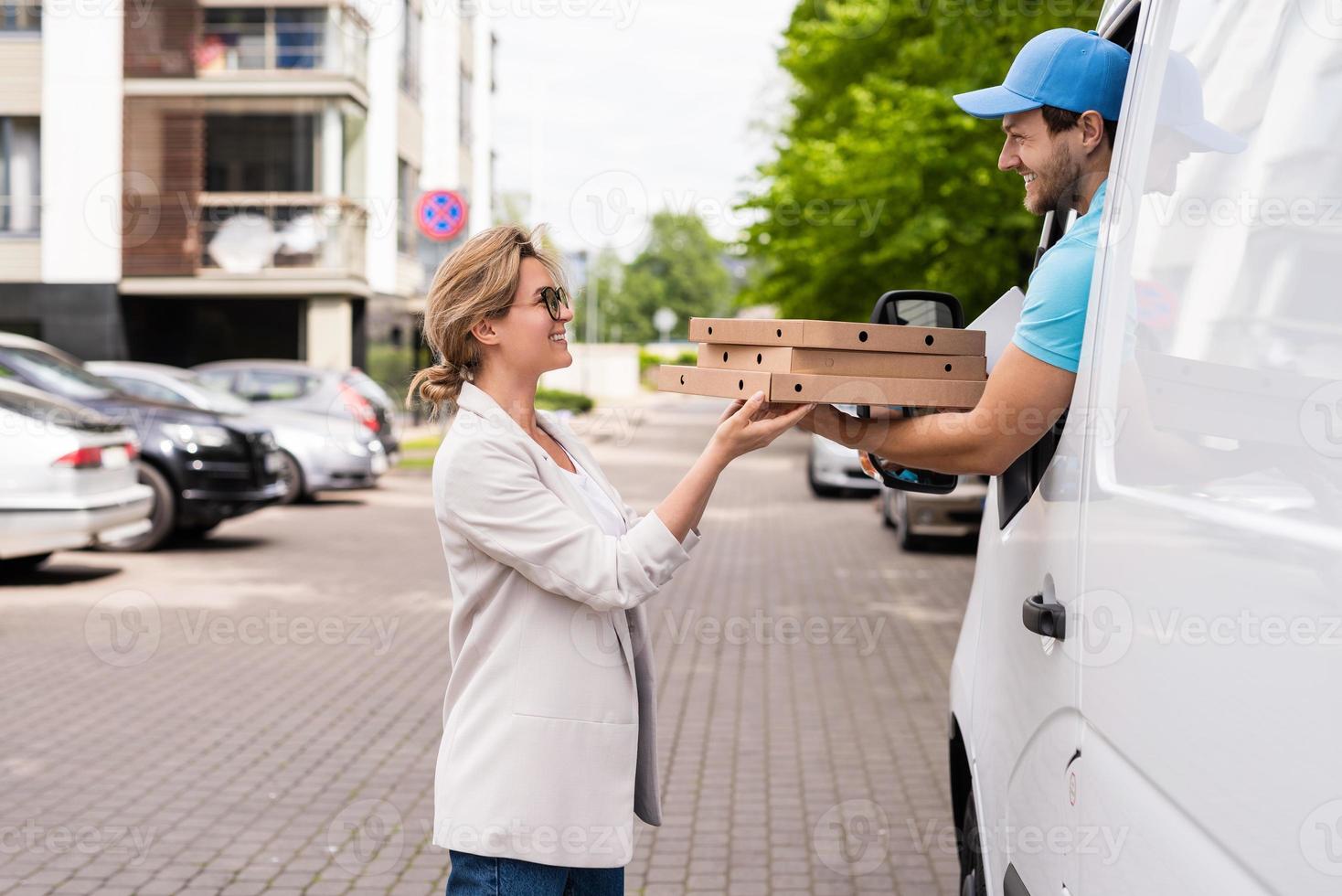 Delivery man in a white van delivers pizza to a woman client photo