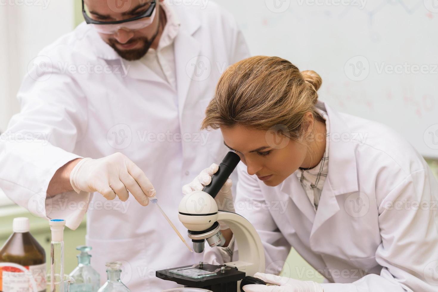 Two Scientist Colleagues Are Using Microscope During Research In A
