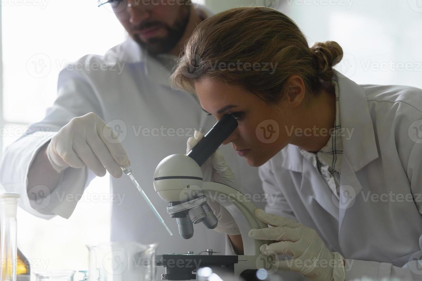 dos colegas científicos están usando microscopio durante la investigación en un laboratorio foto