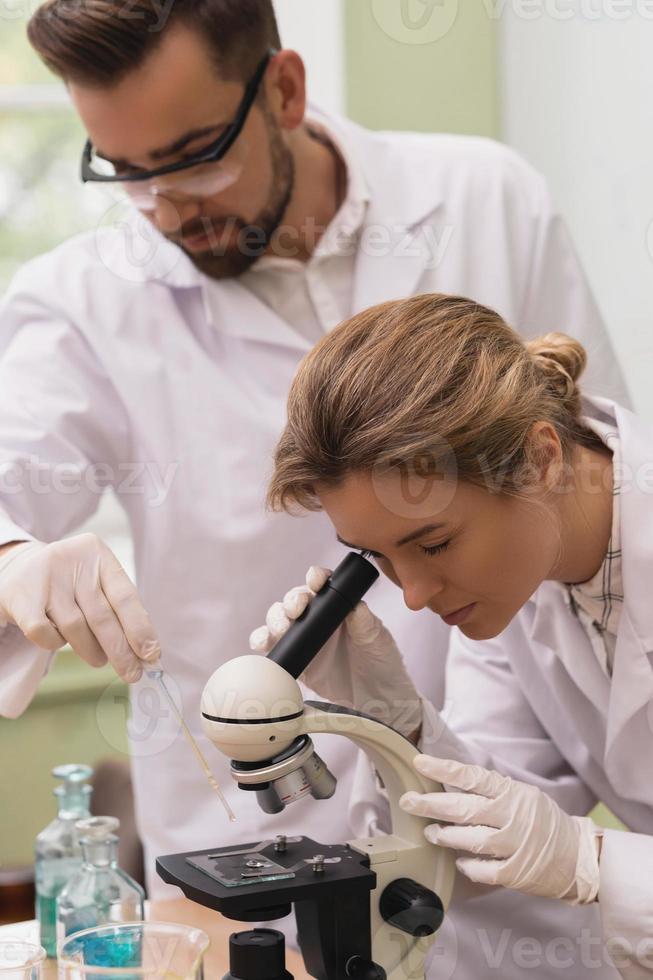 Two scientist colleagues are using microscope during research in a laboratory photo
