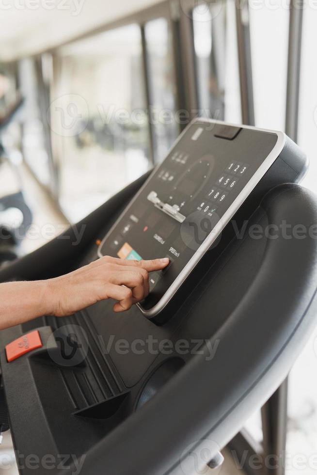 Woman changing settings on a treadmill in a gym photo