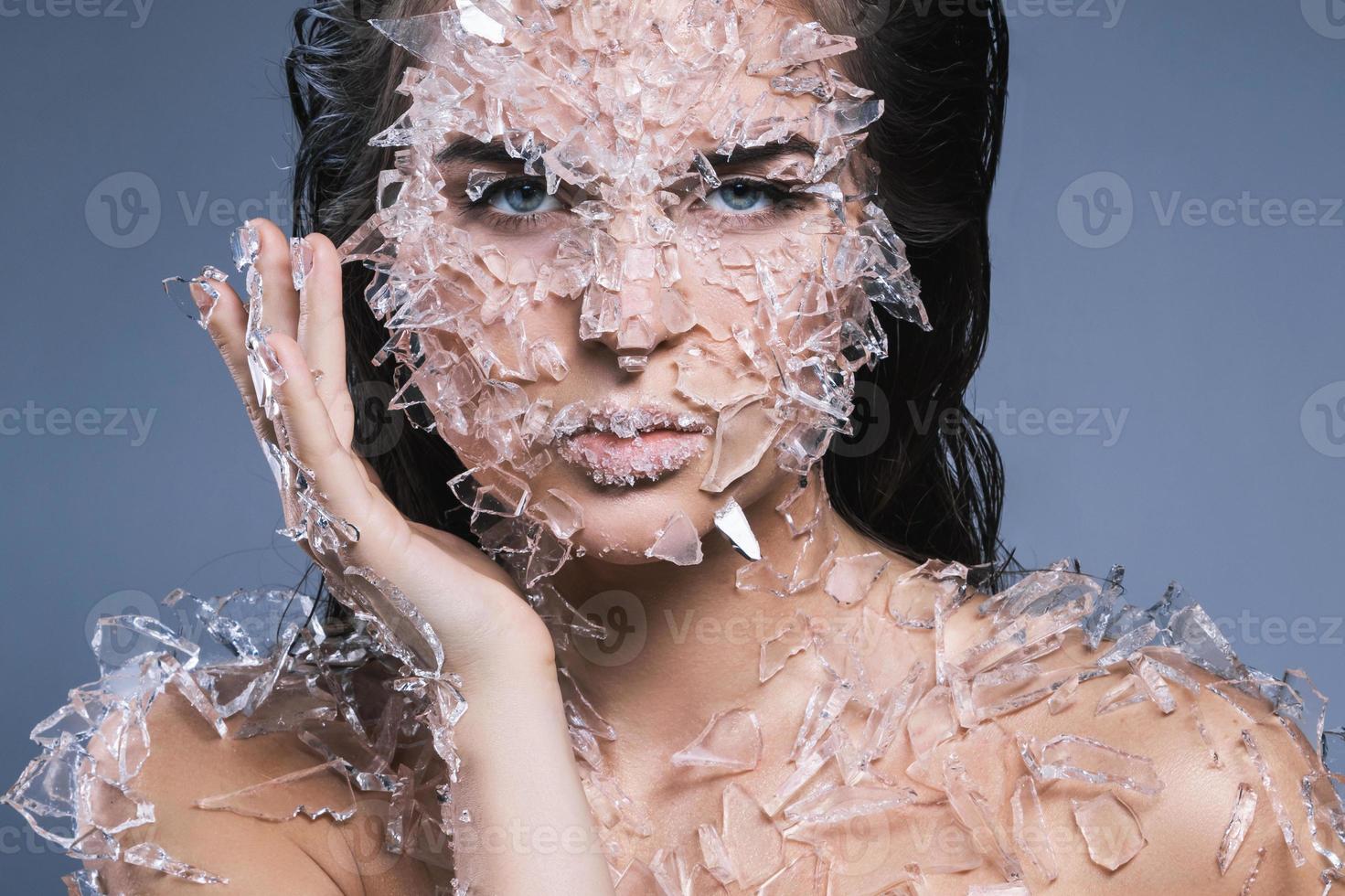 Female face covered with a lot small pieces of glass or ice photo