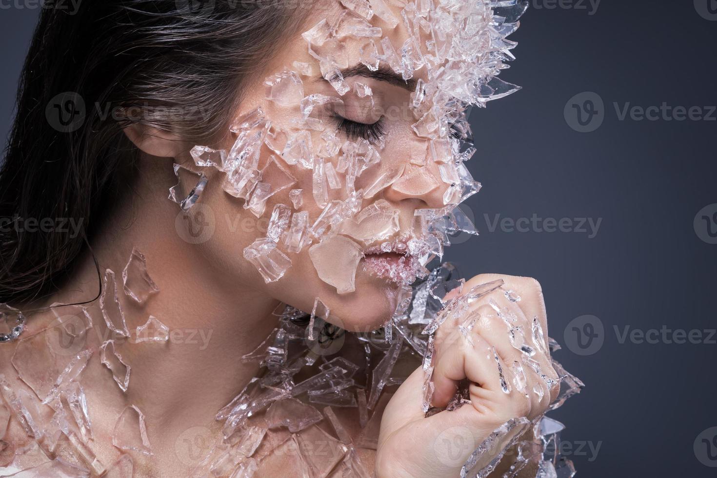 Female face covered with a lot small pieces of glass or ice photo