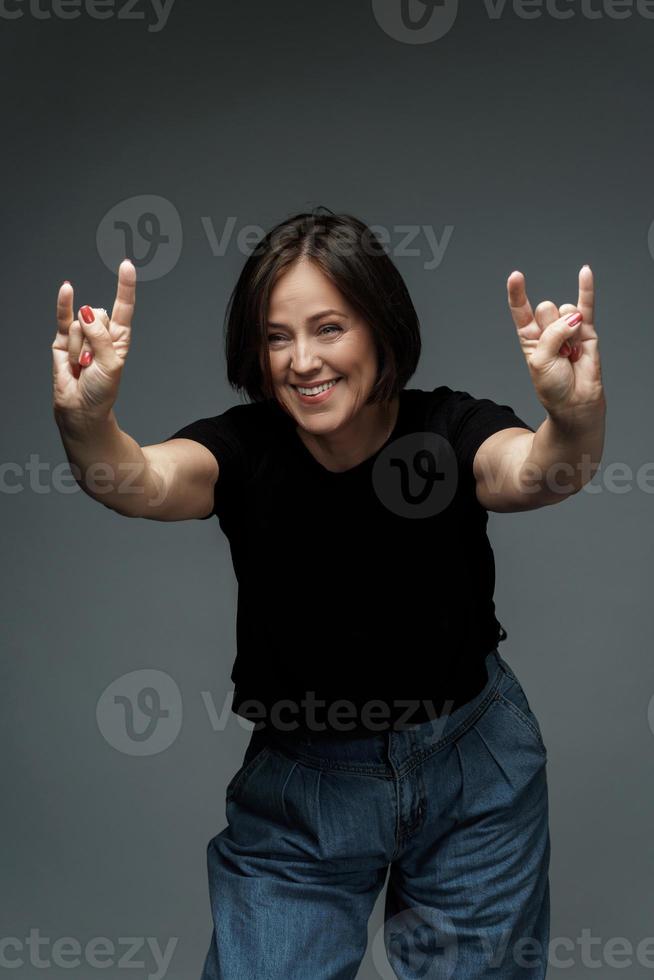 Middle aged woman wearing black t-shirt showing sign of the horns photo