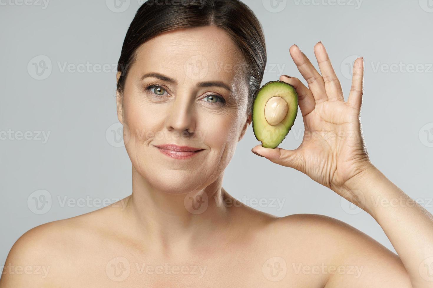Beautiful middle aged woman holding ripe avocado photo