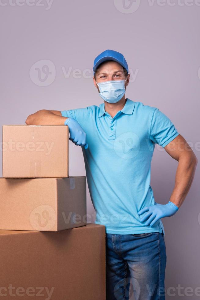 Young delivery man is wearing prevention mask and gloves with a cardboard boxes photo