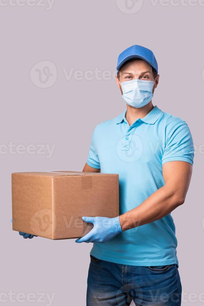 Young delivery man is wearing prevention mask and gloves with a cardboard boxes photo