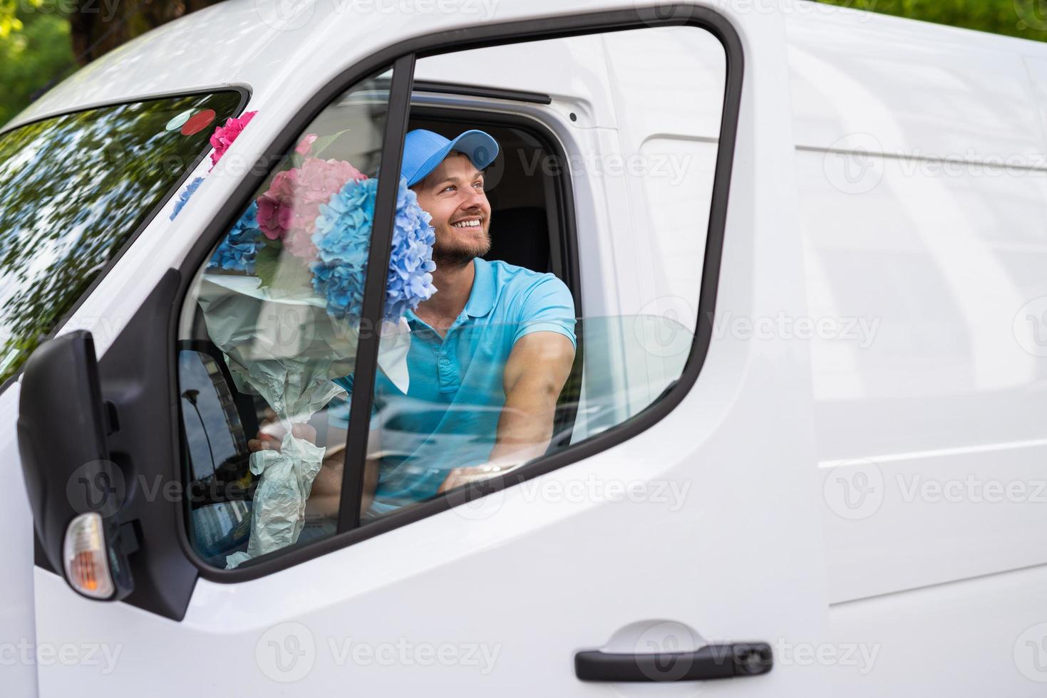 Courier inside the white van during flowers delivery is waiting for a client photo