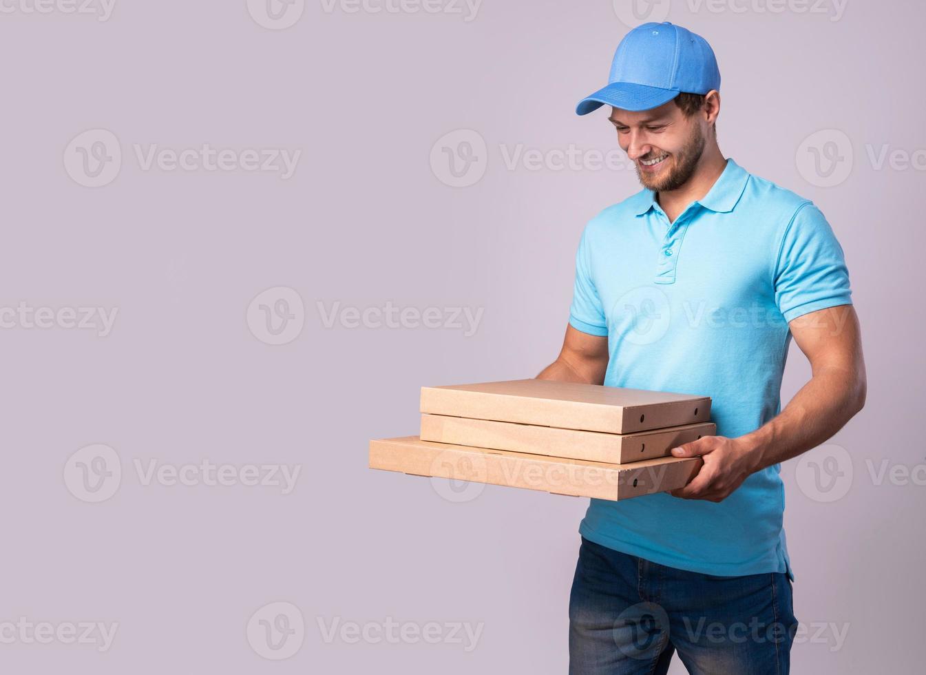 Young delivery man is holding boxes with a delicious pizza photo