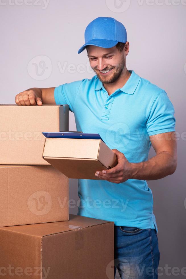 Happy delivery man during work with a packages in a cardboard boxes photo