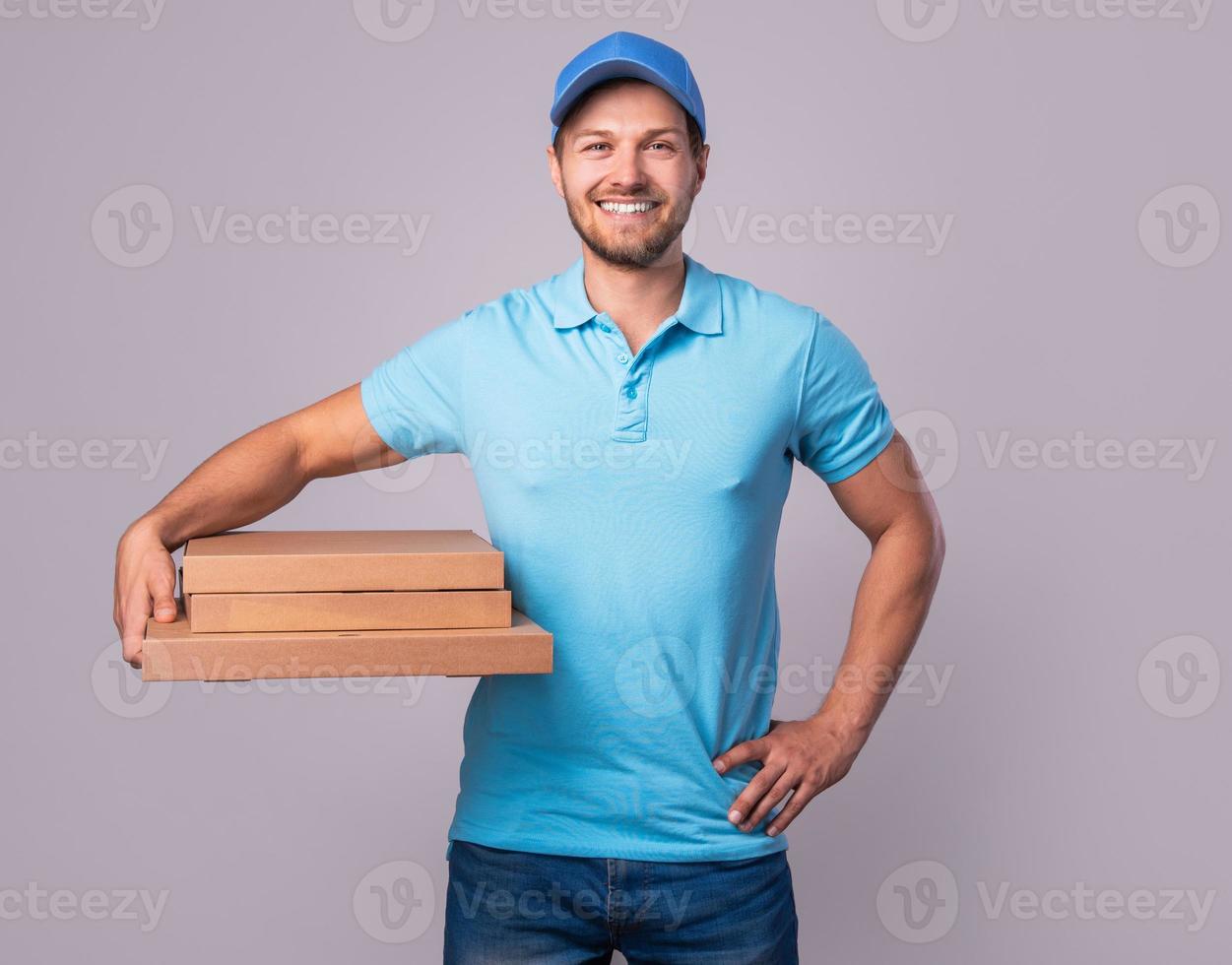 Young delivery man is holding boxes with a delicious pizza photo