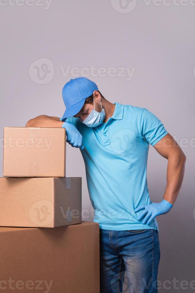 Young delivery man is wearing prevention mask and gloves with a cardboard boxes photo