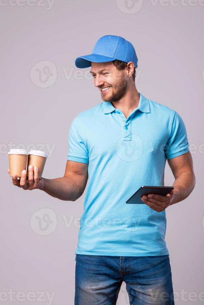 Delivery man is using tablet pc for navigation and brings two cups of coffee photo