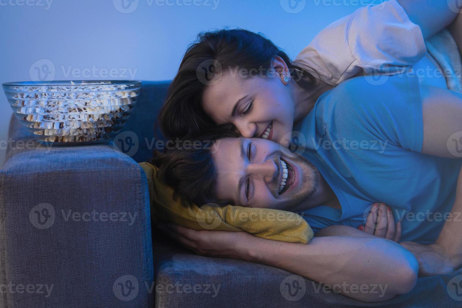 pareja joven y feliz viendo un programa de televisión de comedia foto