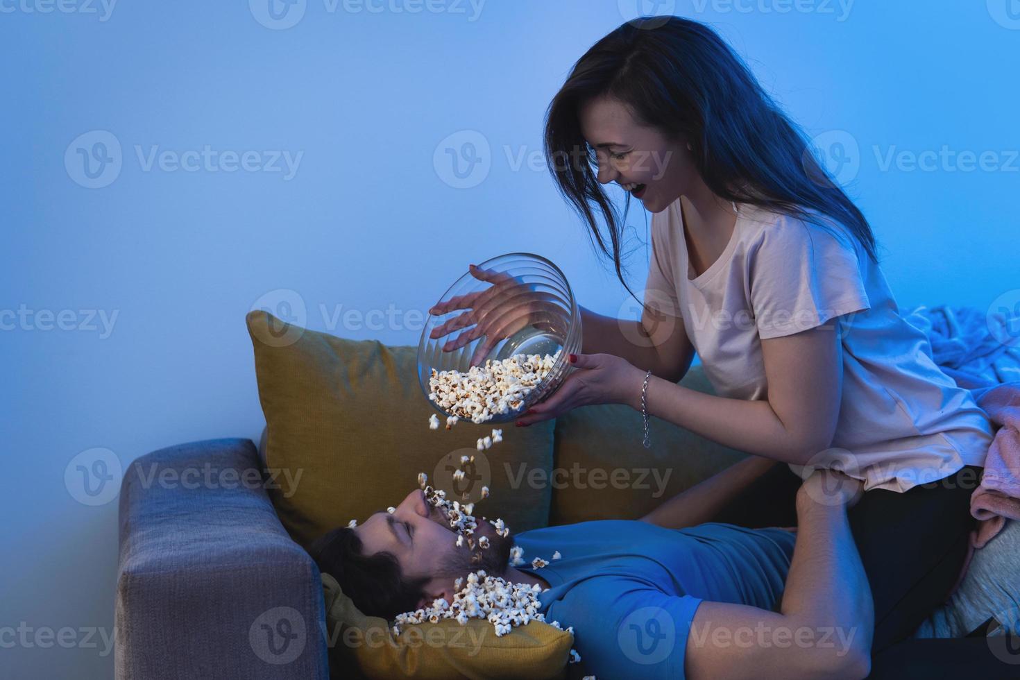 Young and happy couple eating popcorn and watching movie photo