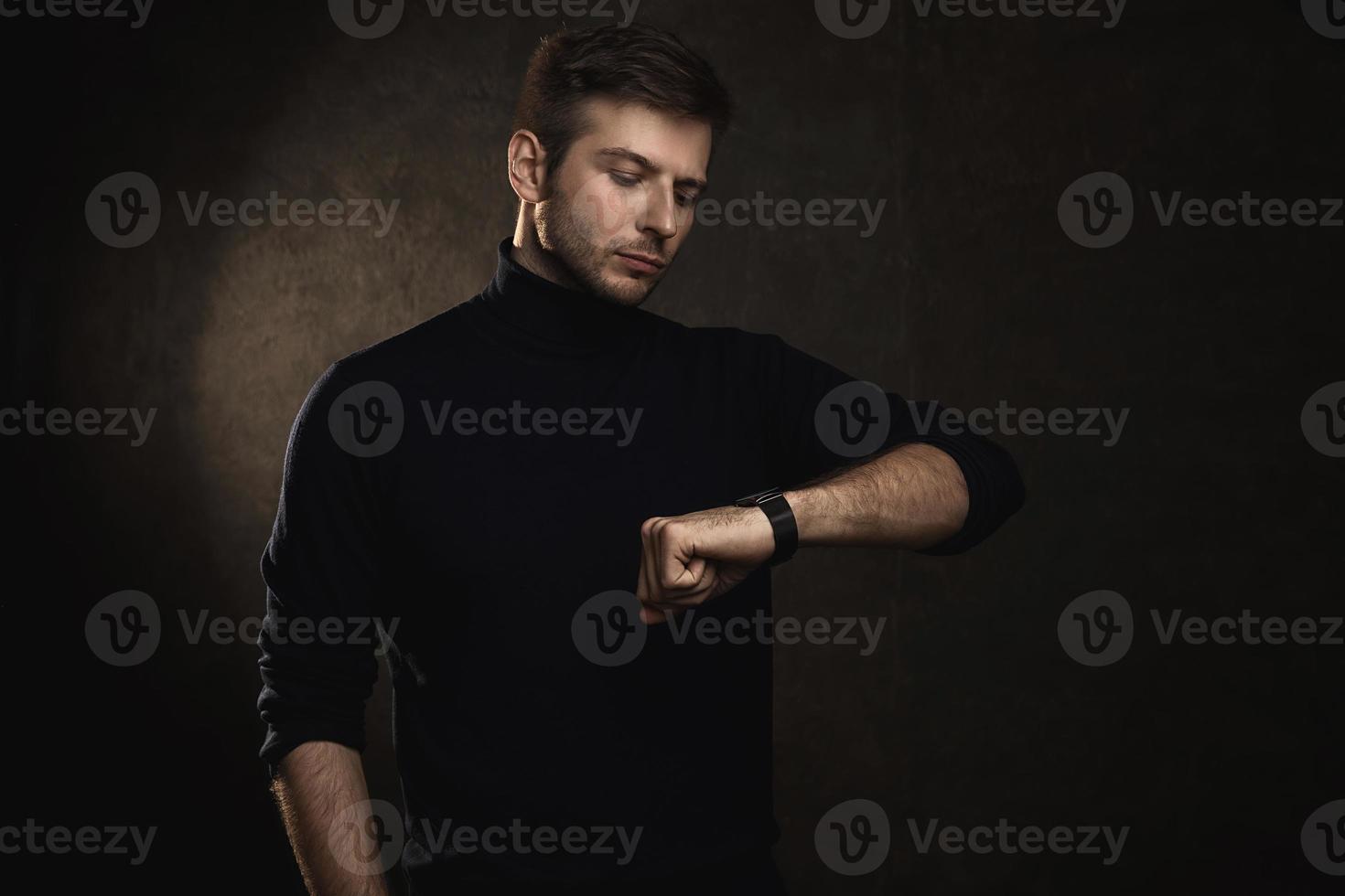 Young handsome man wearing a polo neck is checking time photo