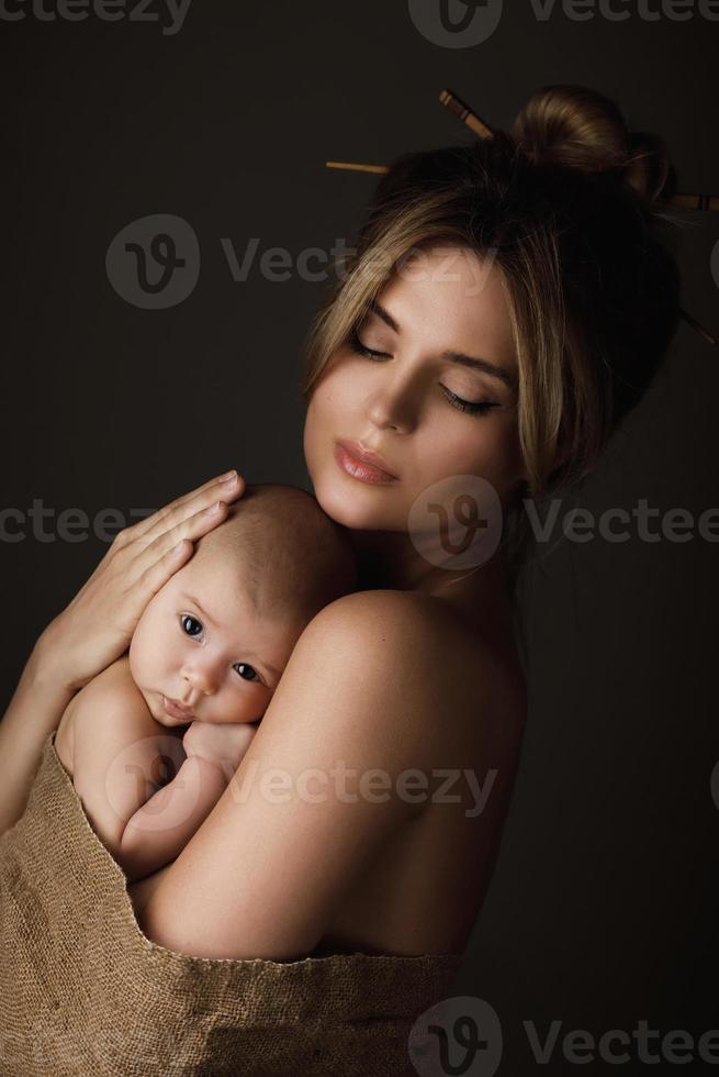 hermosa madre y su pequeño bebé están envueltos en tela de saco foto