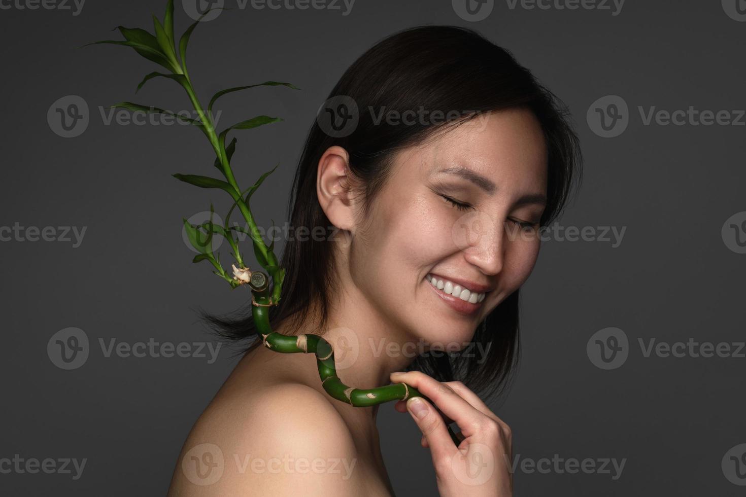 hermosa mujer asiática con una planta de bambú en sus manos foto