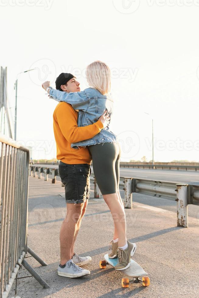 Couple with a longboard on the bridge during the sunset photo