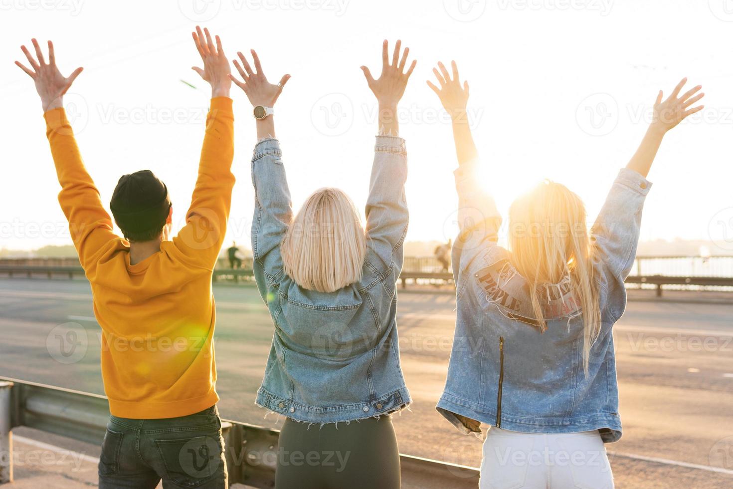 amigos felices están levantando las manos en el aire durante una reunión en la calle foto