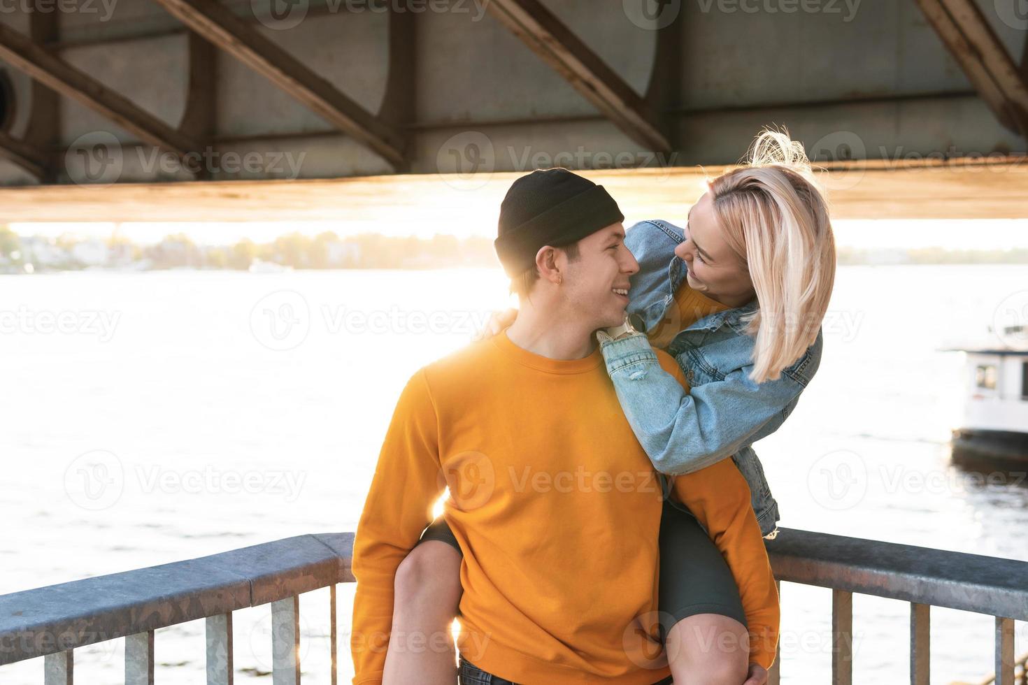 Stylish teenage couple having a date under a bridge at sunset photo