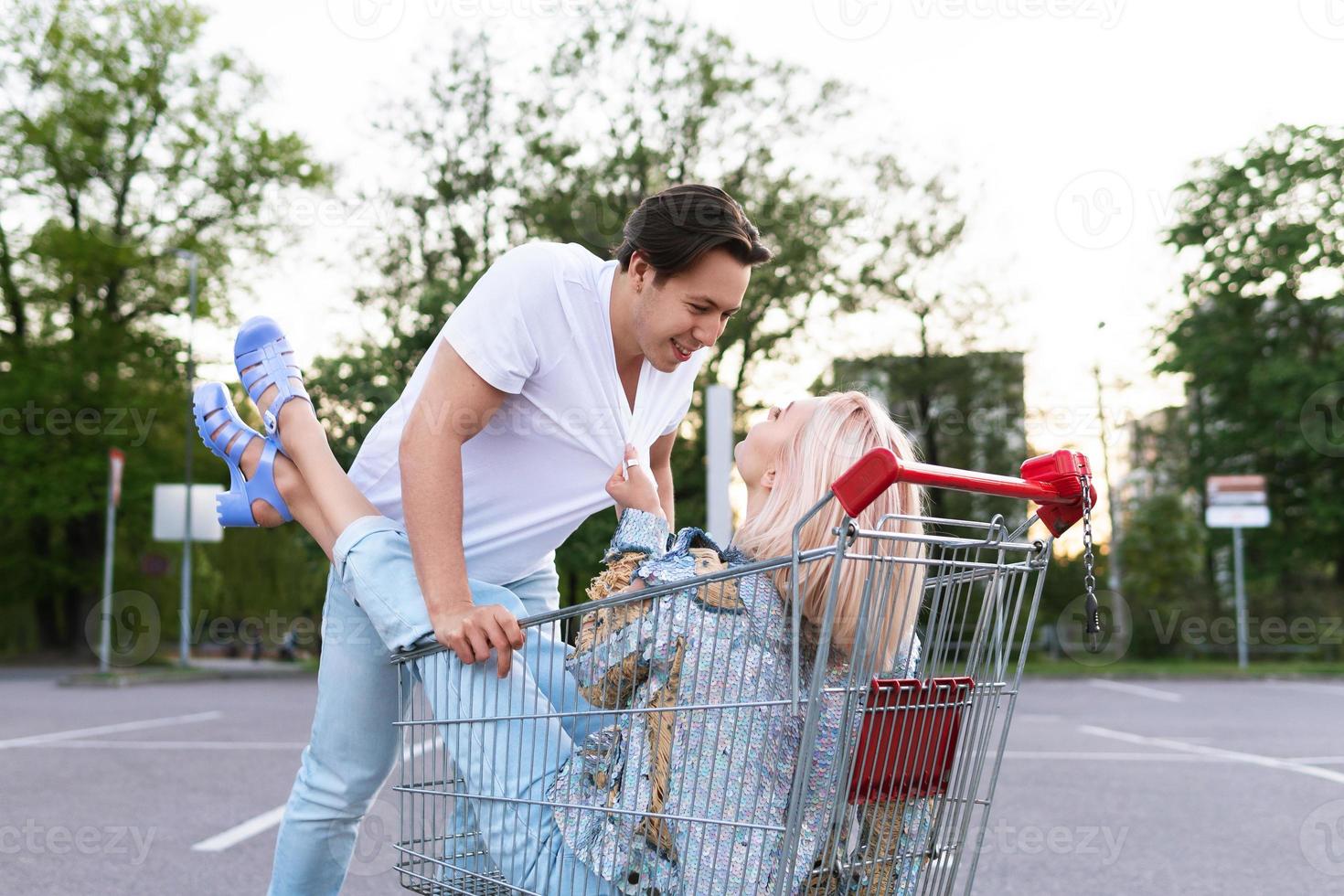 pareja joven con un carrito de compras en el estacionamiento del supermercado foto