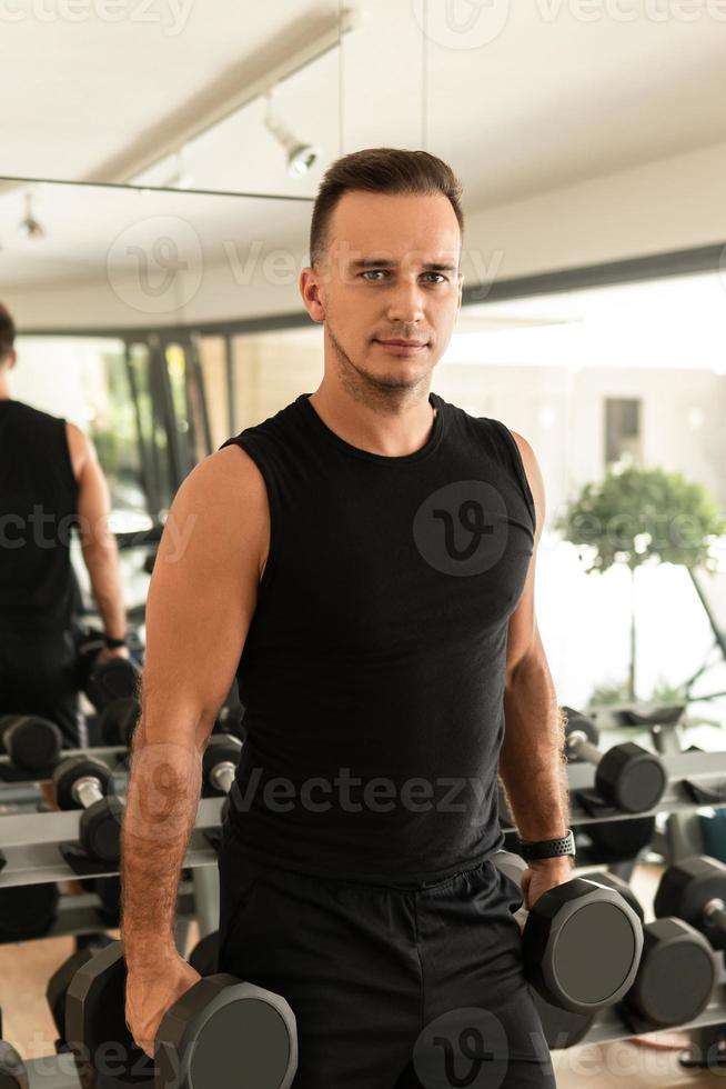 hombre haciendo ejercicio con pesas durante su entrenamiento de culturismo en el gimnasio foto
