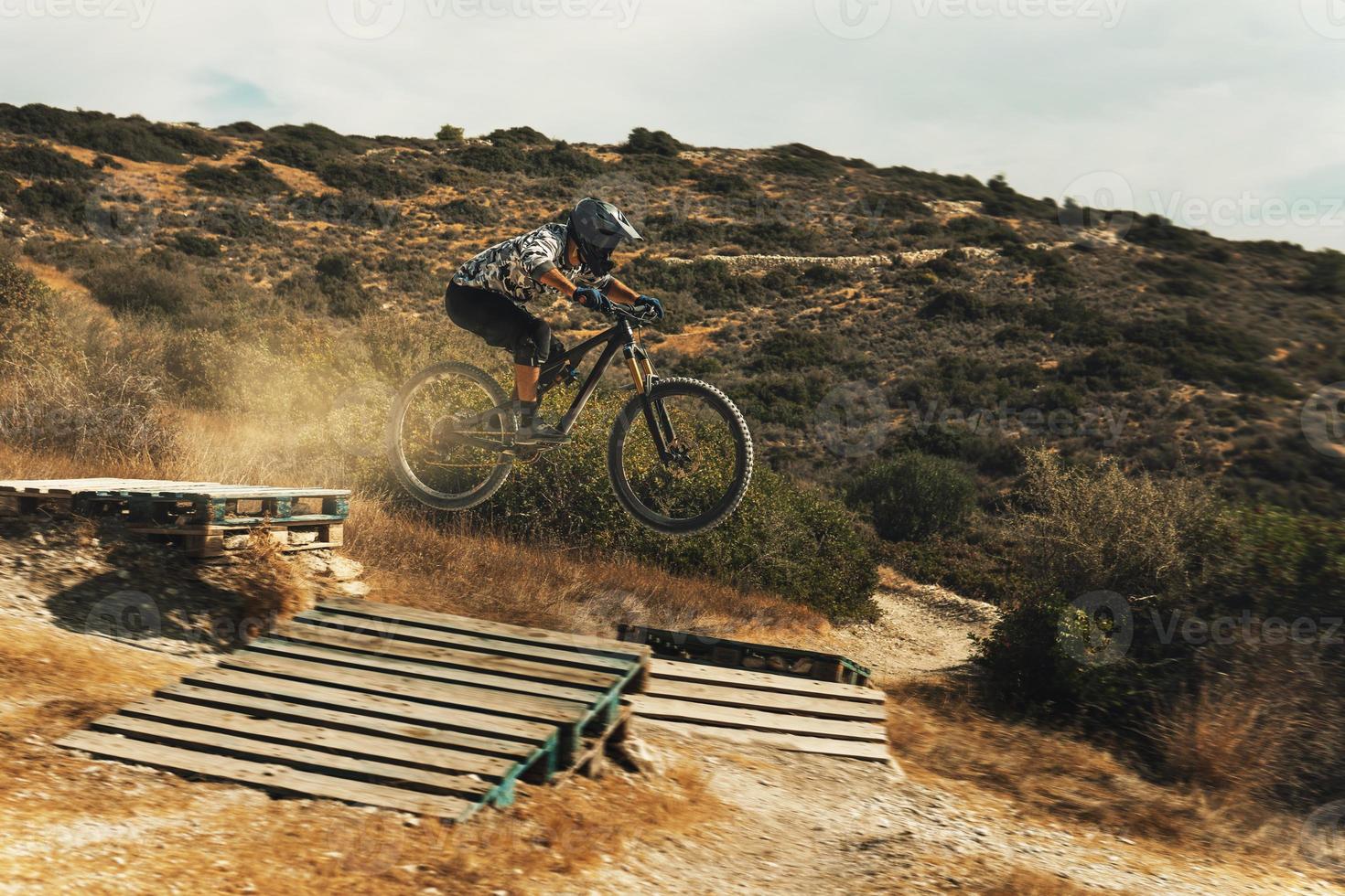 MTB bike rider jumping during downhill ride on his bicycle in mountains photo