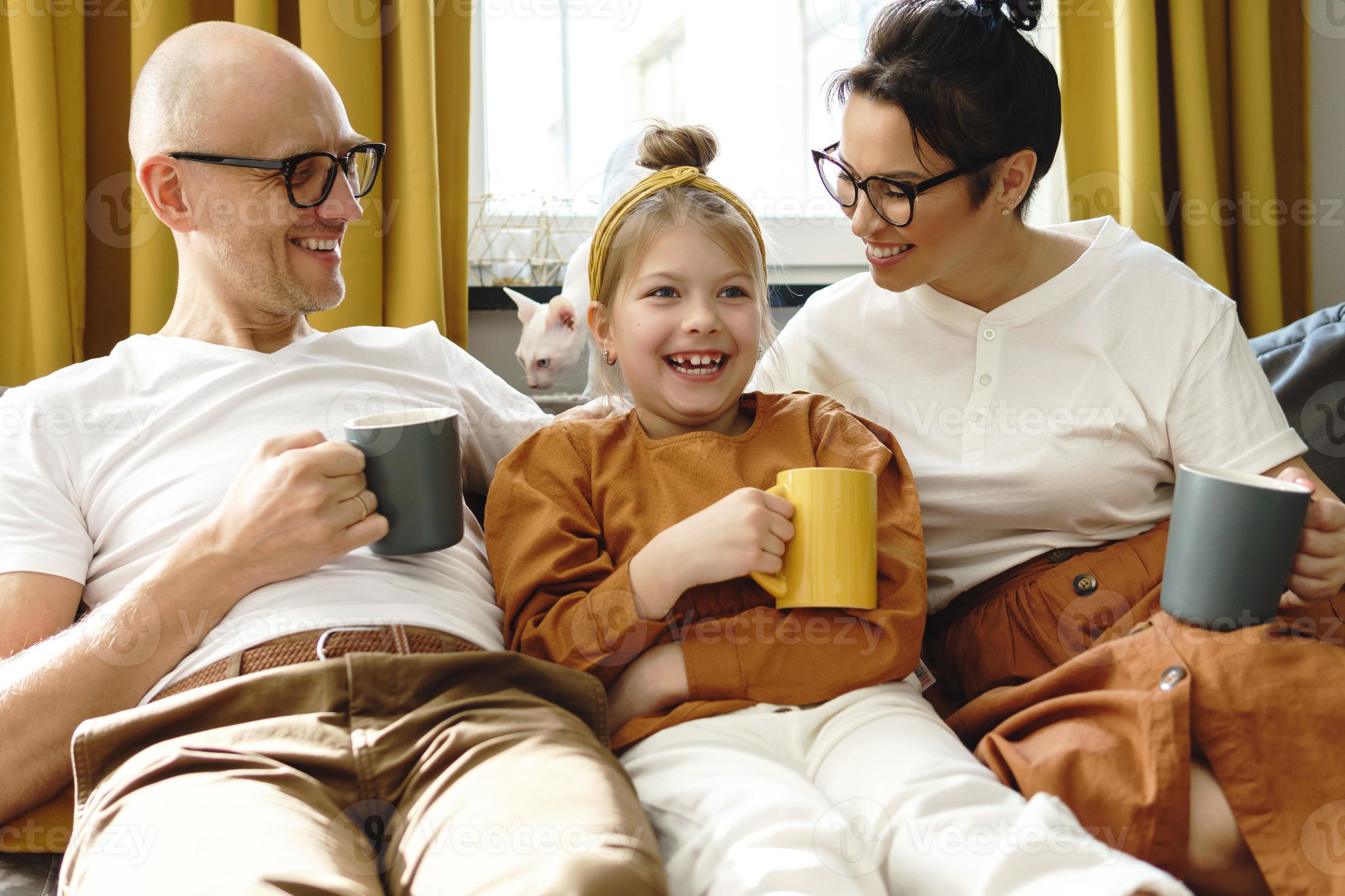 happy-family-sitting-on-the-sofa-and-drinking-hot-tea-16237388-stock